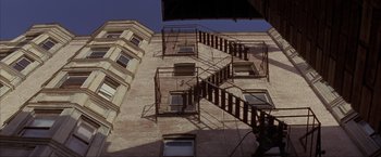 Movie still from “In the Line of Fire” (1993), directed by Wolfgang Petersen – A fire escape on the side of a building; Extreme Wide shot, Low angle