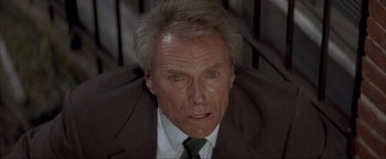 Movie still from “In the Line of Fire” (1993), directed by Wolfgang Petersen – An older man in a suit and tie looking at the camera; Close Up shot, Low angle
