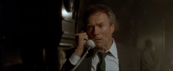 Movie still from “In the Line of Fire” (1993), directed by Wolfgang Petersen – A man talking on a phone while wearing a suit and tie; Close Up shot, Low angle