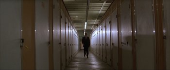 Movie still from “In the Line of Fire” (1993), directed by Wolfgang Petersen – A man in a suit walking down a long hallway; Extreme Wide shot, Low angle