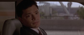 Movie still from “In the Line of Fire” (1993), directed by Wolfgang Petersen – A man wearing a suit and tie sitting in front of a window; Close Up shot, Over the shoulder angle