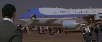 Movie still from “In the Line of Fire” (1993), directed by Wolfgang Petersen – A group of people standing on the ground next to an air force plane; Extreme Wide shot, Low angle