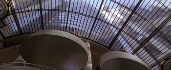 Movie still from “In the Line of Fire” (1993), directed by Wolfgang Petersen – Looking up at a skyscraper through a skylight; Extreme Wide shot, Low angle
