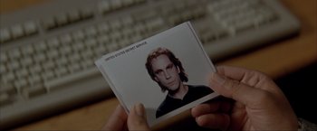 Movie still from “In the Line of Fire” (1993), directed by Wolfgang Petersen – A person is holding up a picture of a man; Extreme Close Up shot, High angle