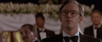 Movie still from “In the Line of Fire” (1993), directed by Wolfgang Petersen – A person wearing a suit and glasses; Close Up shot, Low angle
