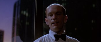 Movie still from “In the Line of Fire” (1993), directed by Wolfgang Petersen – A bald man wearing a black bow tie and a white shirt; Close Up shot, Low angle