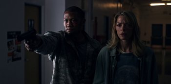 Movie still from “Black Summer” (2019), created by John Hyams – A man and a woman standing next to each other in a room; Medium shot, Over the shoulder angle