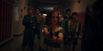 Movie still from “Black Summer” (2019), created by John Hyams – A group of young people standing in a hallway holding remotes; Medium shot, High angle