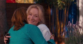 Movie still from “It's Complicated” (2009), directed by Nancy Meyers – Two women hugging each other in front of a bamboo fence; Close Up shot, Over the shoulder angle