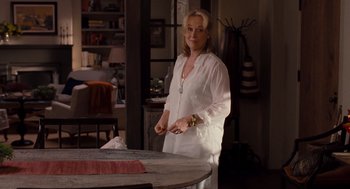 Movie still from “It's Complicated” (2009), directed by Nancy Meyers – A woman standing in front of a wooden table; Medium shot, Over the shoulder angle