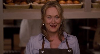 Movie still from “It's Complicated” (2009), directed by Nancy Meyers – A woman wearing an apron standing in front of a counter; Close Up shot, Over the shoulder angle