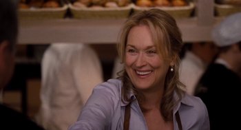 Movie still from “It's Complicated” (2009), directed by Nancy Meyers – A woman smiling for the camera while wearing an apron; Close Up shot, Over the shoulder angle