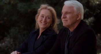 Movie still from “It's Complicated” (2009), directed by Nancy Meyers – A man and a woman sitting next to each other in front of trees; Medium shot, Over the shoulder angle