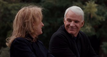 Movie still from “It's Complicated” (2009), directed by Nancy Meyers – A man and a woman sitting next to each other in front of trees; Medium shot, Over the shoulder angle