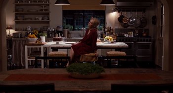 Movie still from “It's Complicated” (2009), directed by Nancy Meyers – A woman sitting at a table in the middle of a kitchen; Wide shot, Over the shoulder angle