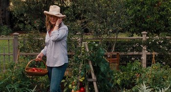 Movie still from “It's Complicated” (2009), directed by Nancy Meyers – A woman wearing a cowboy hat is picking tomatoes; Medium shot, High angle