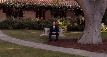 Movie still from “It's Complicated” (2009), directed by Nancy Meyers – A man sitting on a swing in the grass; Wide shot, Over the shoulder angle