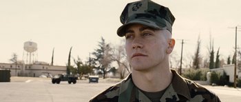 Movie still from “Jarhead” (2005), directed by Sam Mendes – A man in a military uniform is standing in a parking lot; Close Up shot, Low angle