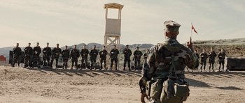 Movie still from “Jarhead” (2005), directed by Sam Mendes – A group of soldiers standing next to each other in a field; Wide shot, Over the shoulder angle