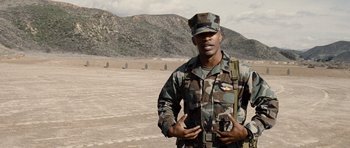 Movie still from “Jarhead” (2005), directed by Sam Mendes – A man in a military uniform standing in the desert; Medium shot, Over the shoulder angle