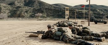 Movie still from “Jarhead” (2005), directed by Sam Mendes – A group of soldiers laying on the ground with guns; Wide shot, High angle