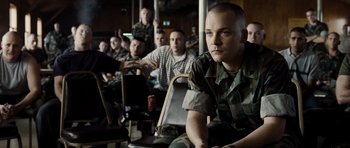 Movie still from “Jarhead” (2005), directed by Sam Mendes – A group of men sitting next to each other in a room; Medium shot, Over the shoulder angle