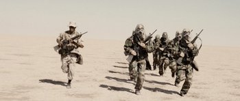 Movie still from “Jarhead” (2005), directed by Sam Mendes – A group of men in military uniforms are running in the desert; Wide shot, Low angle