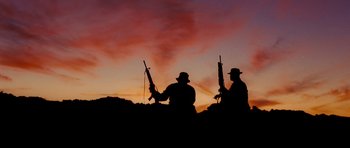 Movie still from “Jarhead” (2005), directed by Sam Mendes – Two men are standing on a hill holding guns; Wide shot, Low angle