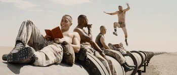 Movie still from “Jarhead” (2005), directed by Sam Mendes – A group of men sitting on top of a truck; Wide shot, Low angle