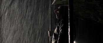 Movie still from “Jarhead” (2005), directed by Sam Mendes – A man holding an open umbrella in the rain; Medium shot, Low angle
