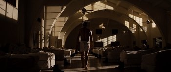 Movie still from “Jarhead” (2005), directed by Sam Mendes – A man walking down a hallway in a room; Wide shot, Low angle