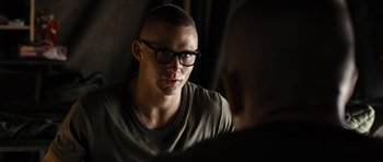 Movie still from “Jarhead” (2005), directed by Sam Mendes – A man with a shaved head wearing glasses; Close Up shot, Over the shoulder angle