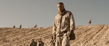 Movie still from “Jarhead” (2005), directed by Sam Mendes – A man standing on top of a dirt hill; Medium shot, Low angle