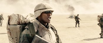 Movie still from “Jarhead” (2005), directed by Sam Mendes – A man in a helmet is standing in the desert; Medium shot, Low angle