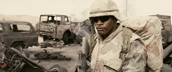 Movie still from “Jarhead” (2005), directed by Sam Mendes – A man in a desert camouflage outfit holding a gun; Close Up shot, Low angle