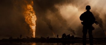 Movie still from “Jarhead” (2005), directed by Sam Mendes – A man standing in front of smoke stacks in the dark; Extreme Wide shot, Low angle