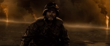 Movie still from “Jarhead” (2005), directed by Sam Mendes – A man in a helmet and a jacket is in the middle of the night; Medium shot, High angle