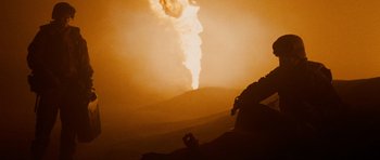 Movie still from “Jarhead” (2005), directed by Sam Mendes – A person taking a picture of a smoke stack; Medium shot, Over the shoulder angle