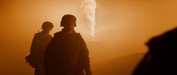 Movie still from “Jarhead” (2005), directed by Sam Mendes – A man standing in front of a smoke filled sky; Medium shot, Low angle