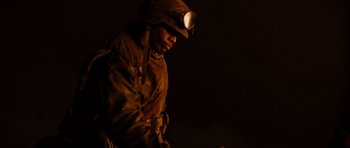 Movie still from “Jarhead” (2005), directed by Sam Mendes – A man wearing a helmet and a gas mask is standing in the dark; Close Up shot, Low angle