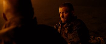 Movie still from “Jarhead” (2005), directed by Sam Mendes – A man sitting in a dark room looking at the camera; Close Up shot, Over the shoulder angle