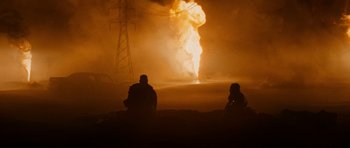 Movie still from “Jarhead” (2005), directed by Sam Mendes – Two people sitting in front of an explosion; Extreme Wide shot, Over the shoulder angle