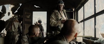 Movie still from “Jarhead” (2005), directed by Sam Mendes – A man in a military uniform standing in front of a group of men; Medium shot, Over the shoulder angle
