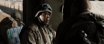 Movie still from “Jarhead” (2005), directed by Sam Mendes – A man wearing a helmet and a camouflage uniform; Close Up shot, Over the shoulder angle