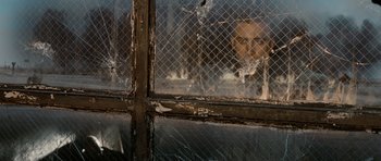 Movie still from “Jarhead” (2005), directed by Sam Mendes – A window that is broken in half with broken glass on it; Close Up shot, Over the shoulder angle