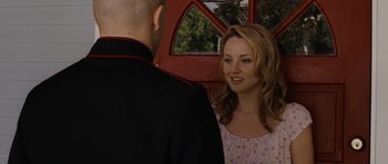 Movie still from “Jarhead” (2005), directed by Sam Mendes – A man and a woman standing next to each other in front of a red door; Close Up shot, Over the shoulder angle