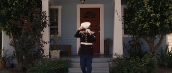 A man in a military uniform standing in front of a house