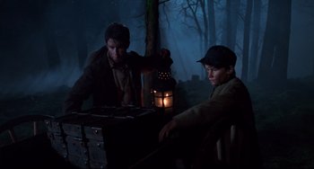 Movie still from “Jumanji” (1995), directed by Joe Johnston – Two young men sitting at a table in the dark; Medium shot, Low angle