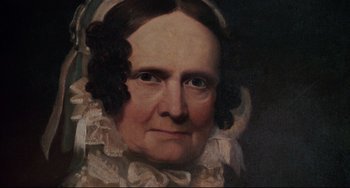 Movie still from “Jumanji” (1995), directed by Joe Johnston – An older woman with a white dress and a white hat; Close Up shot, High angle