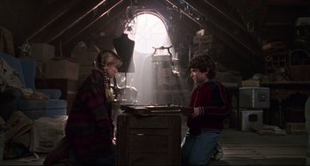 Movie still from “Jumanji” (1995), directed by Joe Johnston – Two young people are playing a game in the attic; Medium shot, Low angle